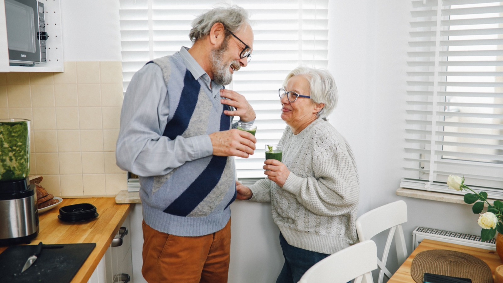 Couple de seniors souriants dans leur cuisine, rente viagère versée chaque mois