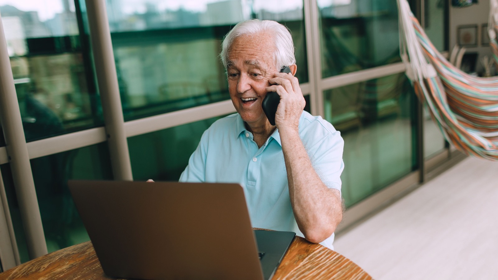 Senior au téléphone devant son ordinateur, viager libre d'un bien non occupé